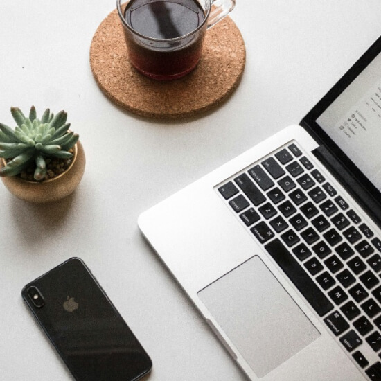laptop, phone, and coffee on table